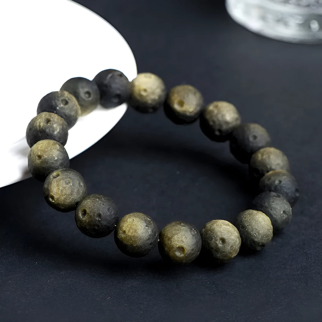 Obsidian crater ball bracelet with textured meteorite-like beads on elasticated cord