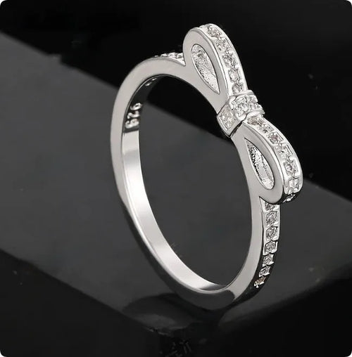 Silver bow-shaped ring with rhinestone and zircon crystal details on a model finger.