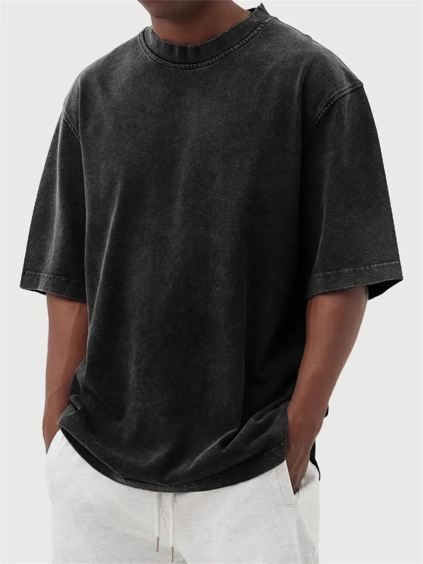 Man wearing a loose-fit, stone-washed polyester T-shirt in a solid colour with a distressed finish.