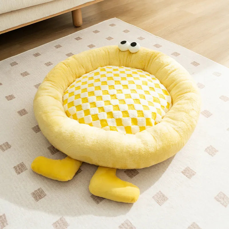 Blue plush kennel sleeping mat for small dog with raised edges, shown on a wooden floor.