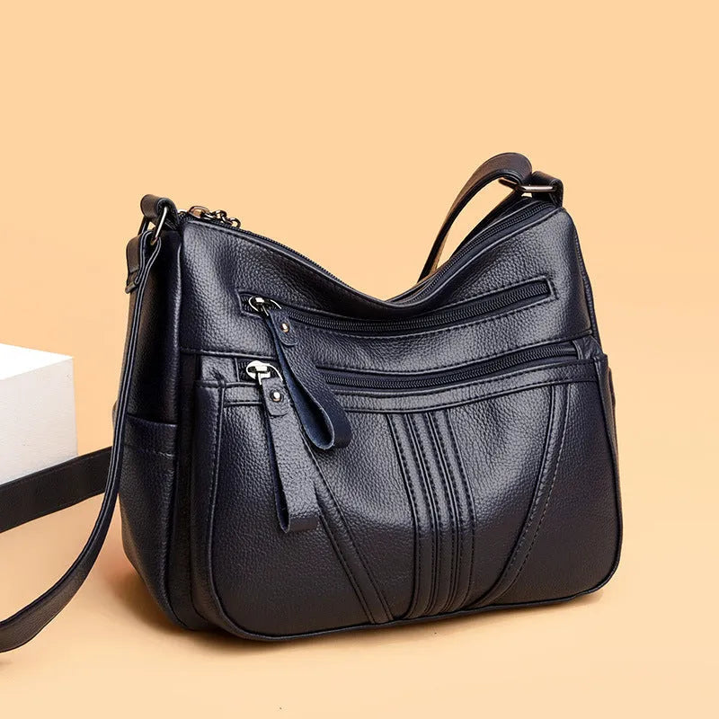 Genuine leather horizontal square messenger bag in black with contrast stitching and a front slit pocket.