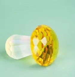 A set of colourful crystal mushroom decorations in transparent, green, red, and yellow on a white surface.