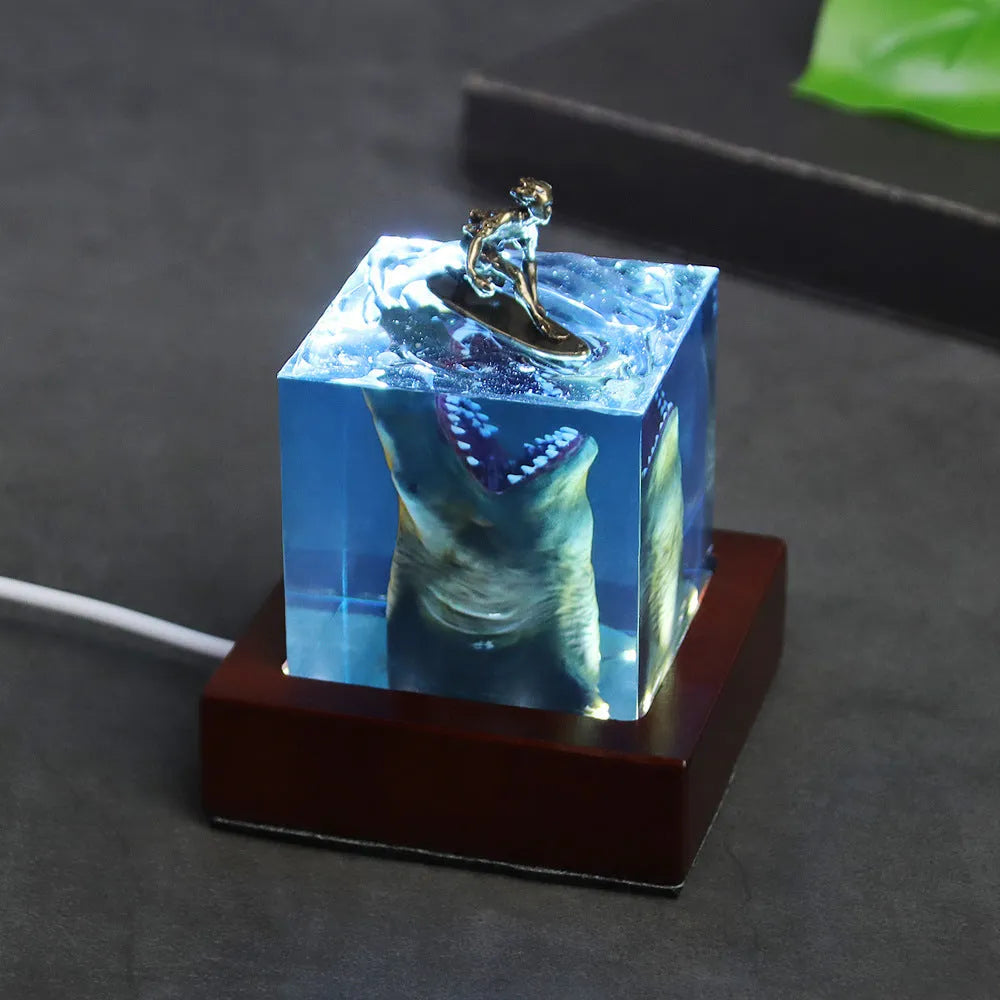 Epoxy resin shark surfer night light ornament on a desk with glowing micro landscape.