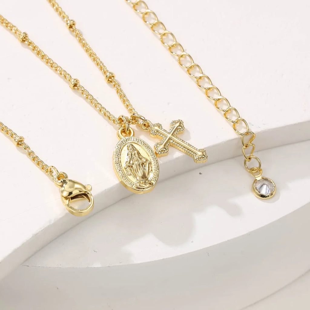 Gold-coloured geometric cross pendant necklace featuring the Virgin Mary, on a matching chain.