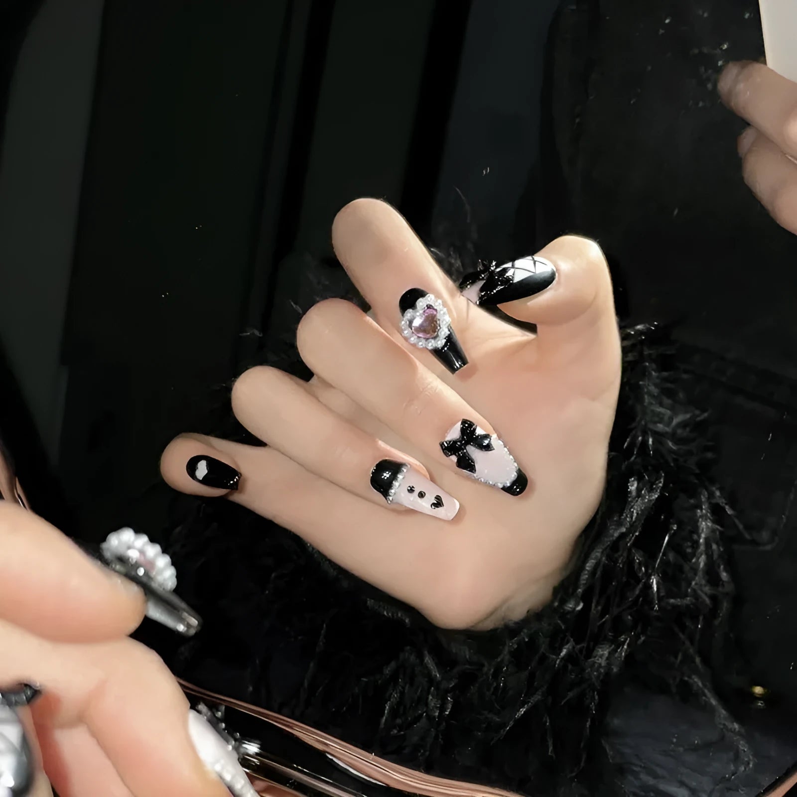 Hand-painted black and peach heart-shaped press-on nails with a cat's eye shine, shown in a set.
