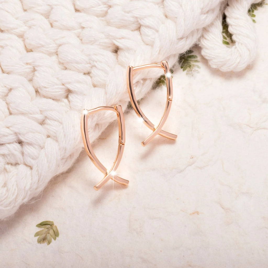 Rose gold plated cross-shaped drop earrings on a copper base.