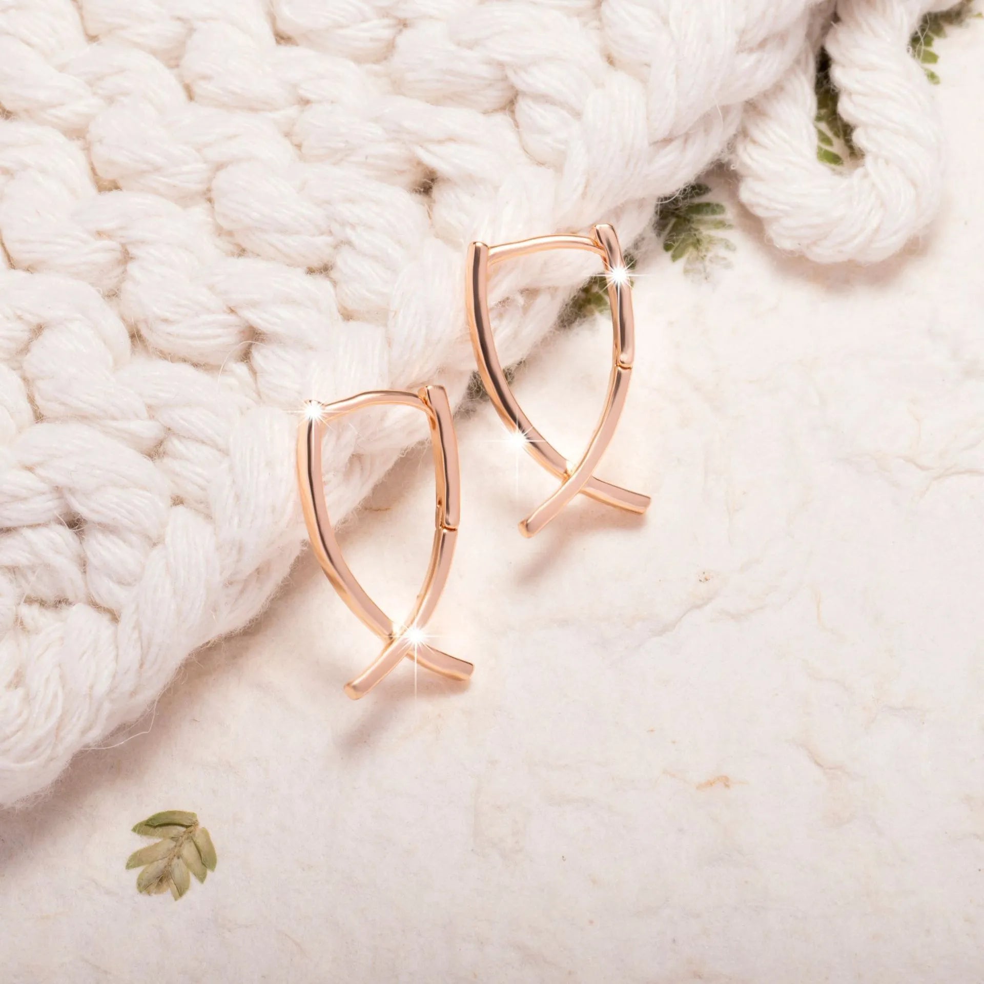 Rose gold plated cross-shaped drop earrings on a copper base.