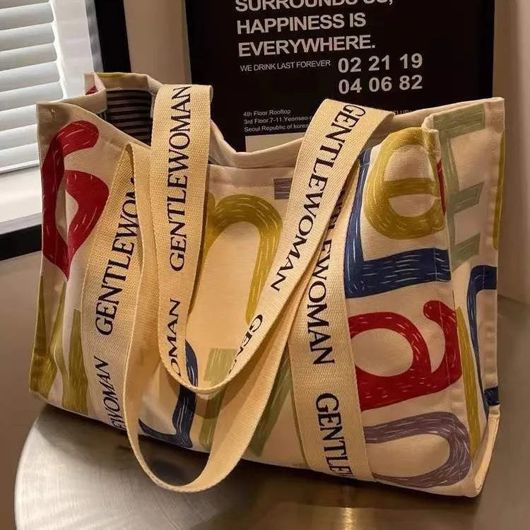 Large canvas tote bag with printed design, featuring two fabric handles, shown in available colour style options.