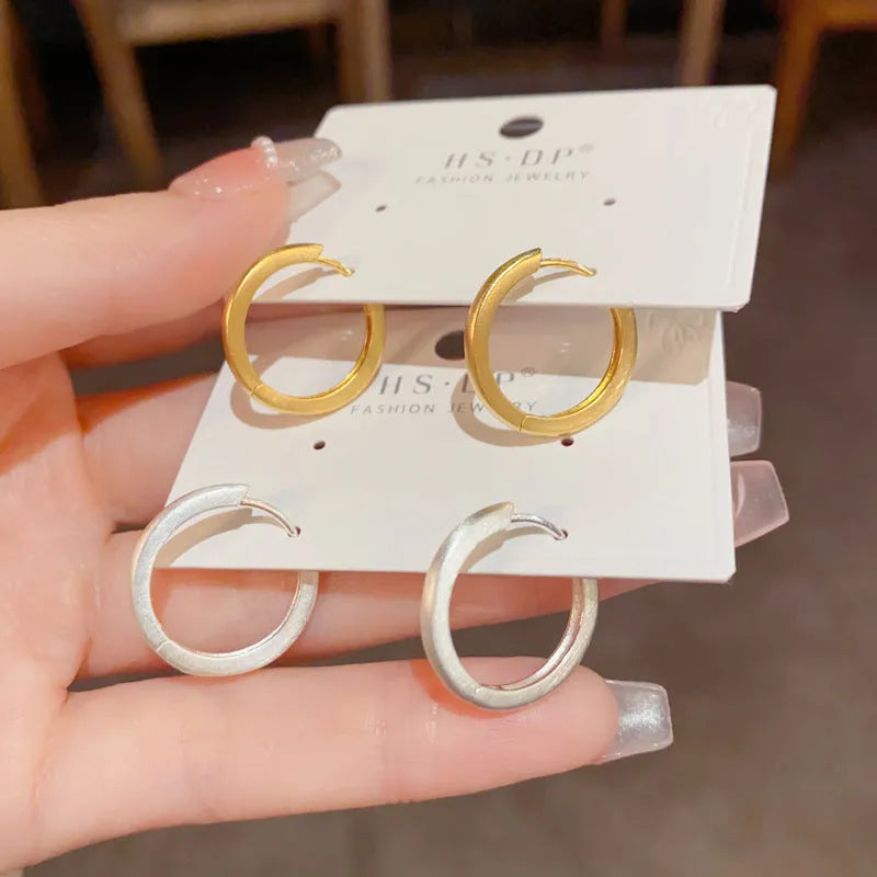 Women's simple geometric round copper ear clips with real gold plating in gold and silver colours showing eyelet design detail