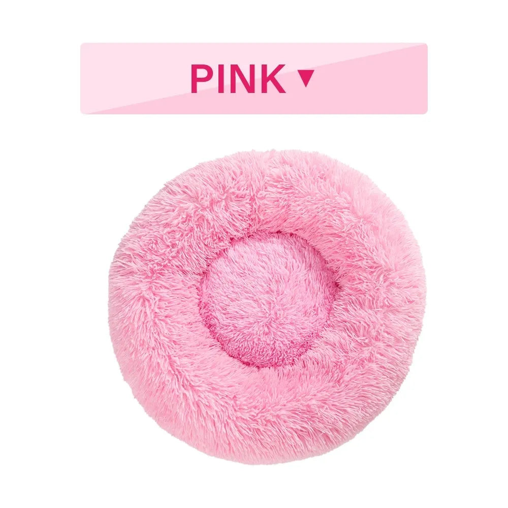 Fluffy donut-shaped dog bed in long plush material, shown in a light grey colour.