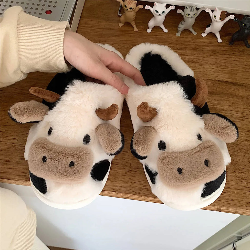 White cartoon cow design faux fur slippers for women with a non-slip textured sole.