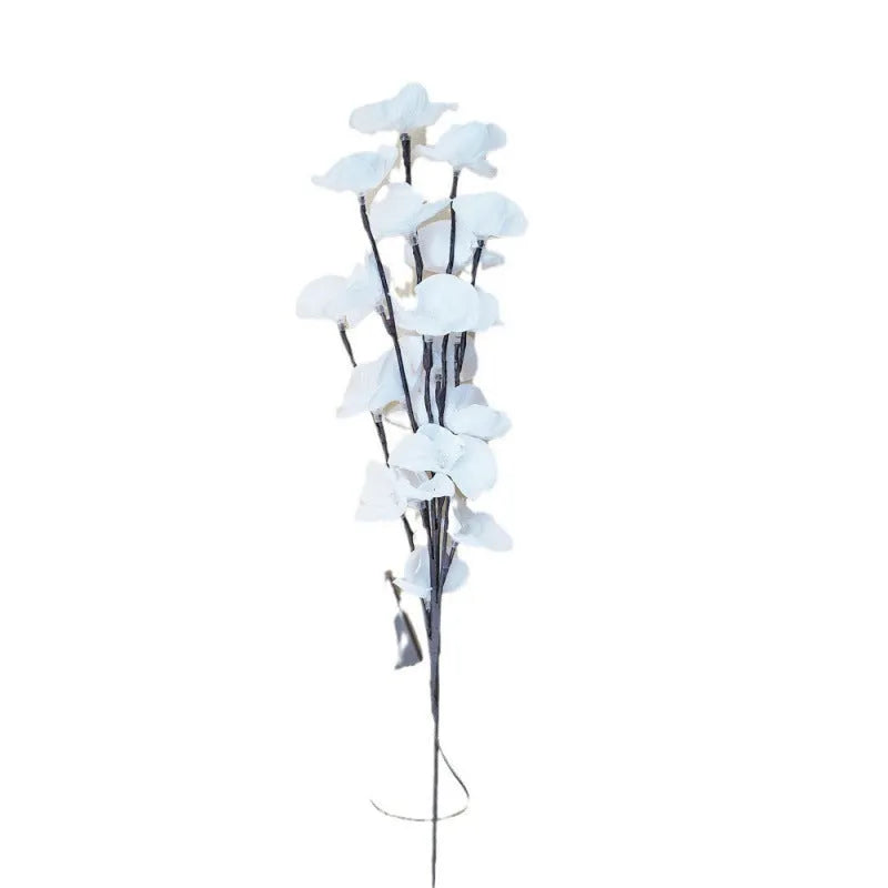 Pink artificial Phalaenopsis orchid branch LED decorative light, 65cm tall, on a bedside table.