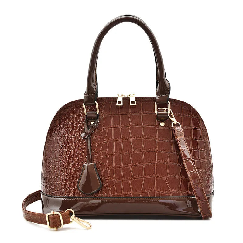 Large shiny black crossbody shoulder bag with a structured shell shape.