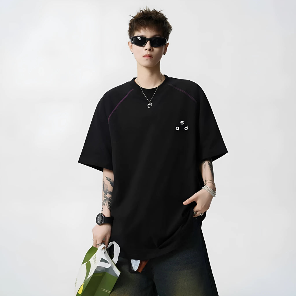 Man wearing a black loose-fit cotton t-shirt with a white letter print on the front.