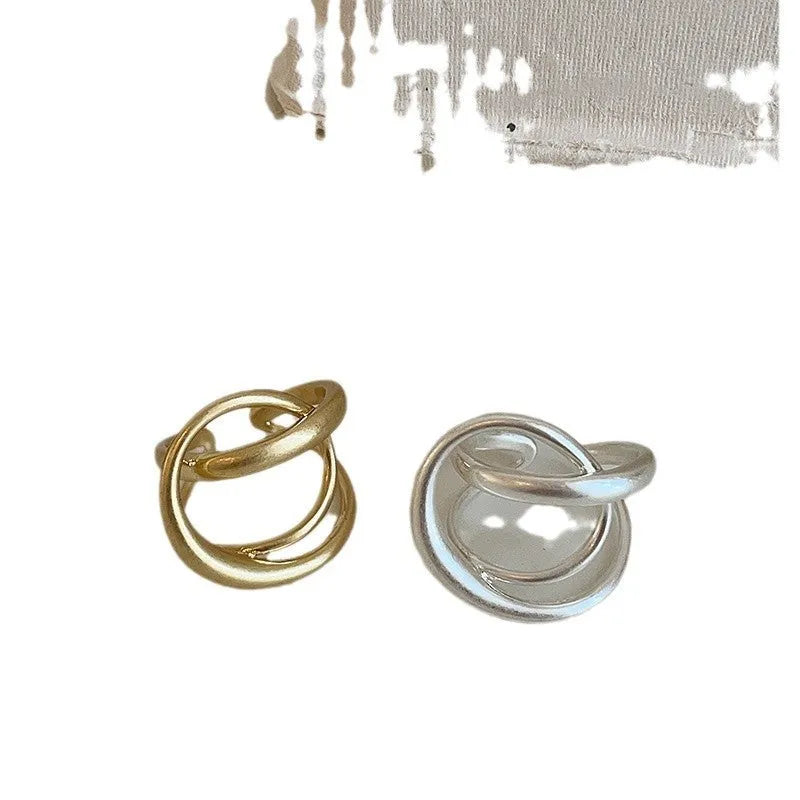 Geometric open ring with 3D interlaced matte metal design in gold or silver finish.