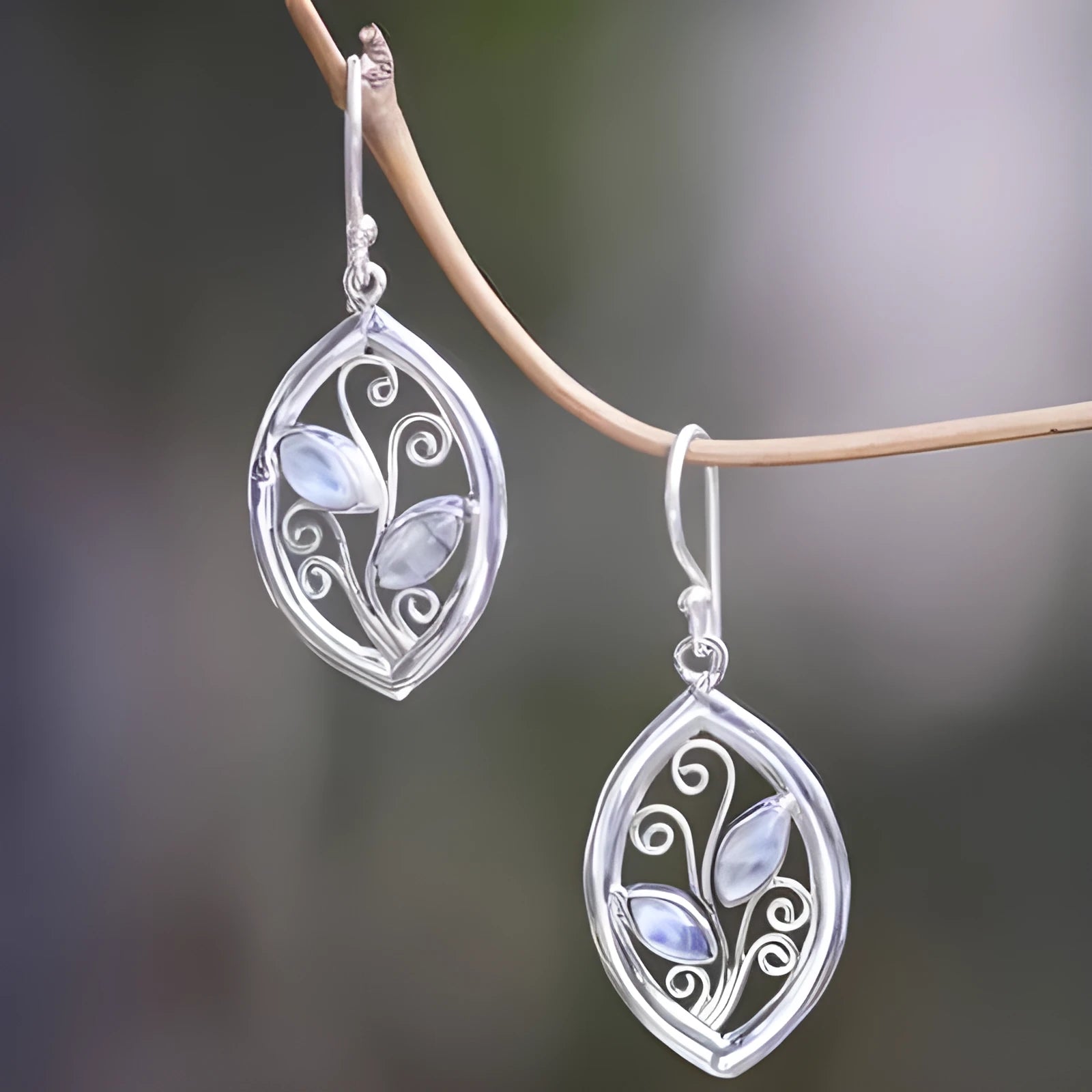 Silver-coloured alloy earrings shaped like a leaf with colourful moonstone stones embedded in the design.