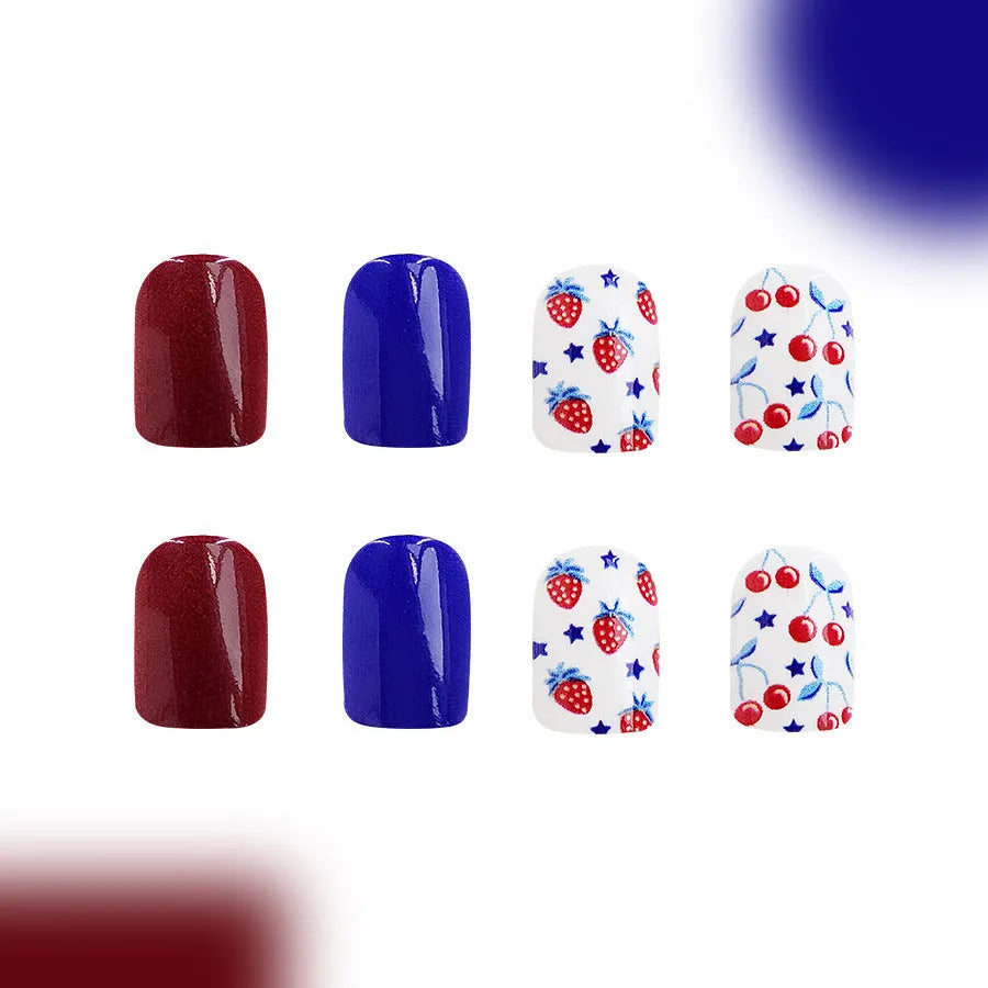 Short glossy false nails with strawberry and cherry pattern on red and blue background.