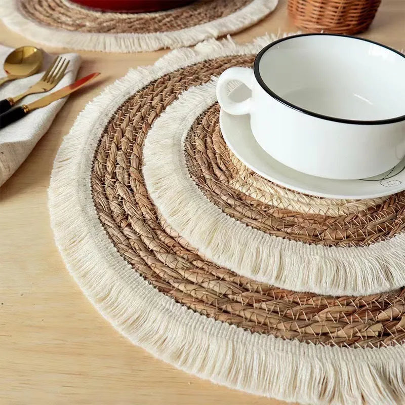 Round natural papyrus straw placemat with decorative tassels on a table