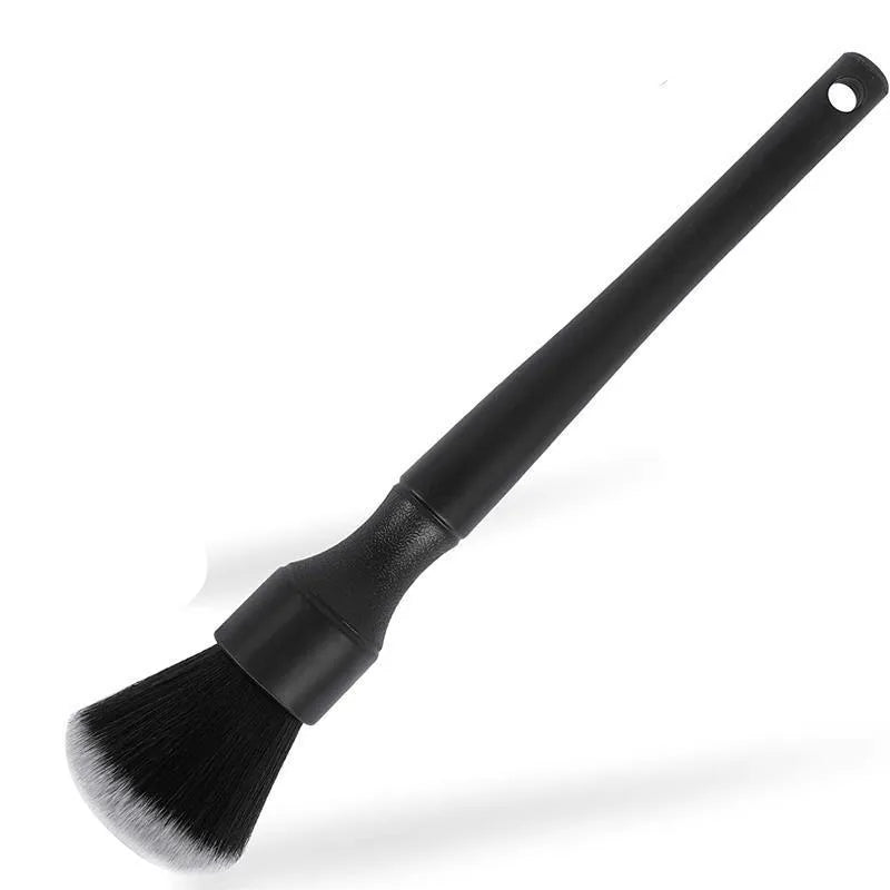 Black ultra-soft pig hair car detailing brush for interior cleaning on a car dashboard.