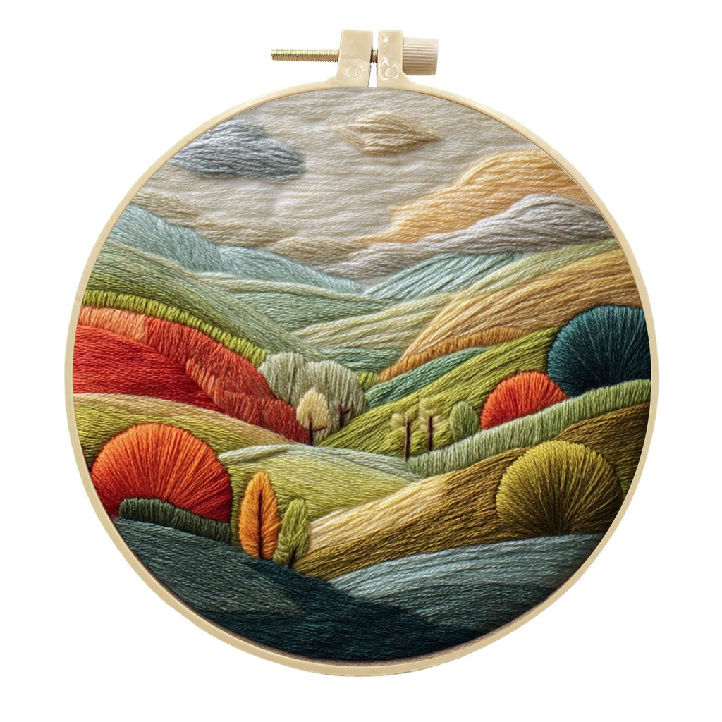 Embroidery DIY kit with bamboo frame, cotton fabric printed with a landscape scene, threads, and needles laid out