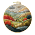 Embroidery DIY kit with bamboo frame, cotton fabric printed with a landscape scene, threads, and needles laid out