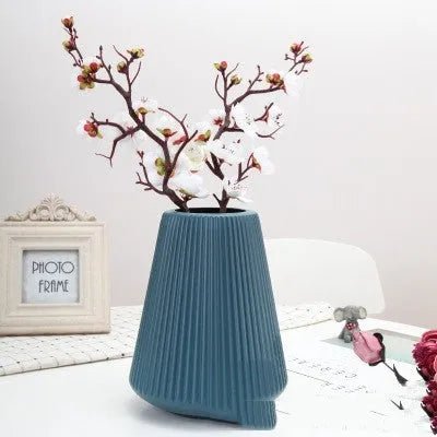 Blue melamine plastic decorative flower vase on a wooden desktop.