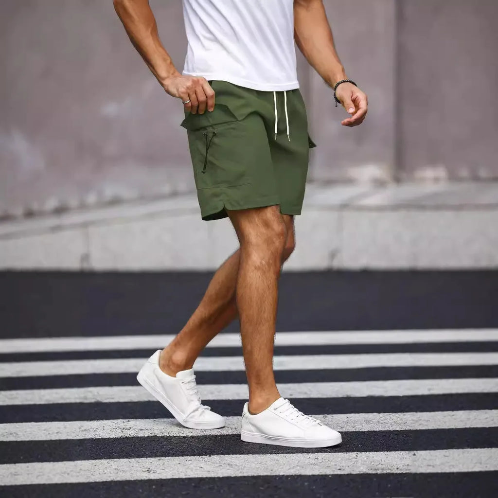 Man wearing loose fit army green straight leg workwear shorts made from cool silk cotton fabric.