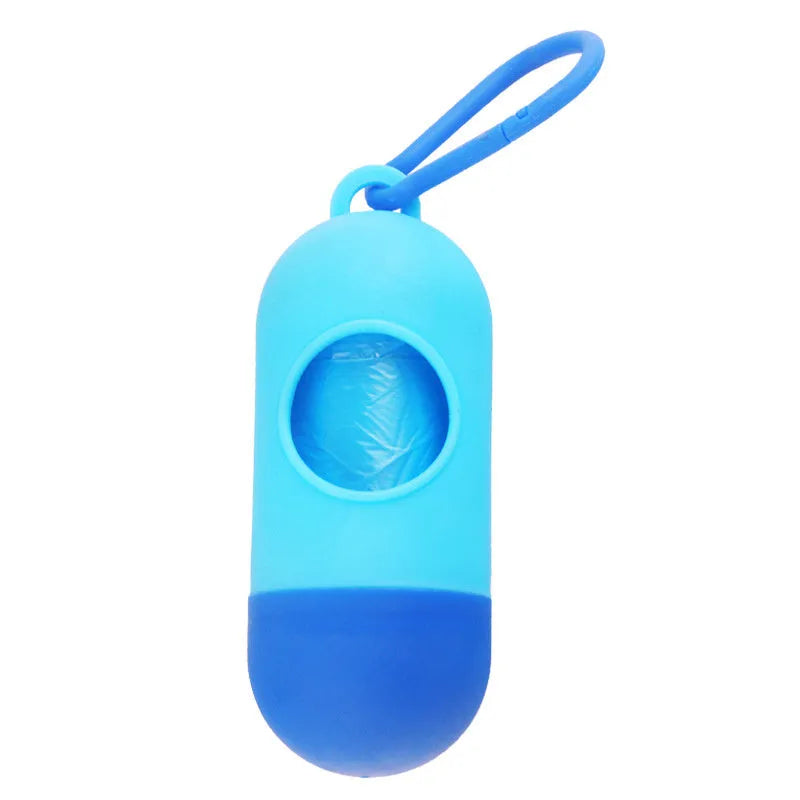 A compact black dog poop bag holder with a side hook and Velcro strap, shown next to a roll of waste bags.