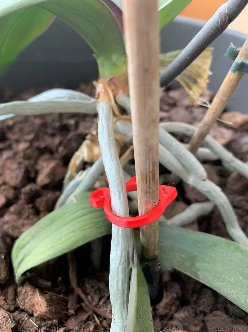 Decorative red plastic cat-shaped clip for gardening plant support.