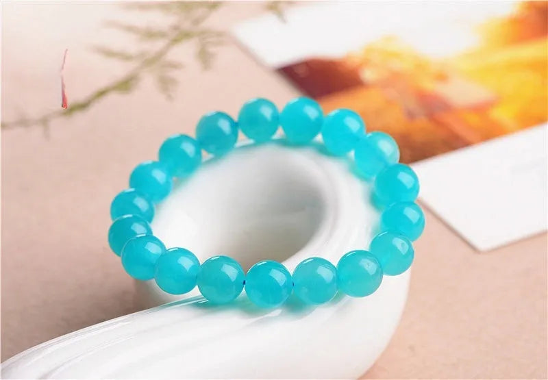 Natural blue-green Amazonite polished beads scattered on a surface, with a finished crystal bracelet.