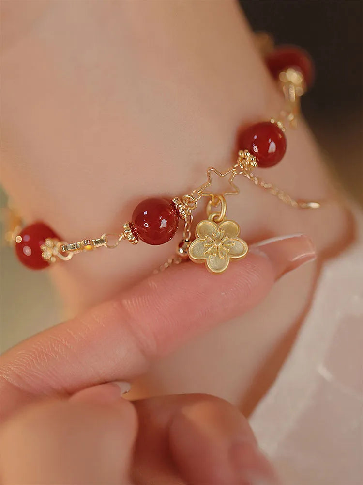 Handmade red agate double layer bracelet with floral peach blossom design on a white background.