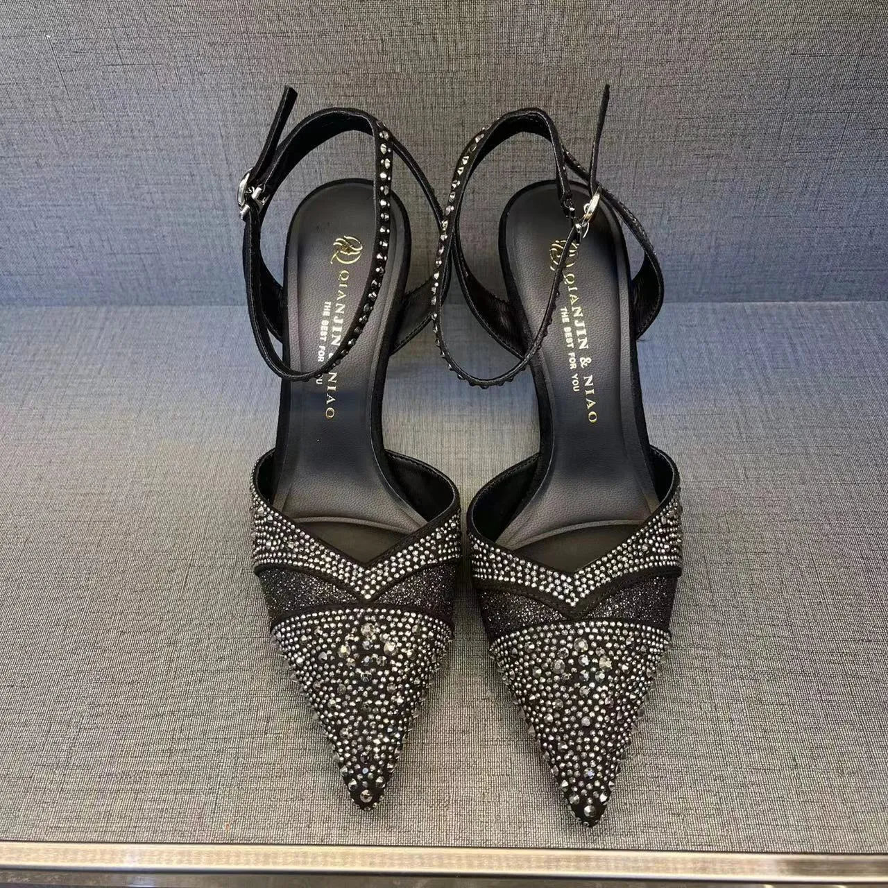 Women's silver high heel shoe with stiletto heel, pointed toe, and red sole on a white background.