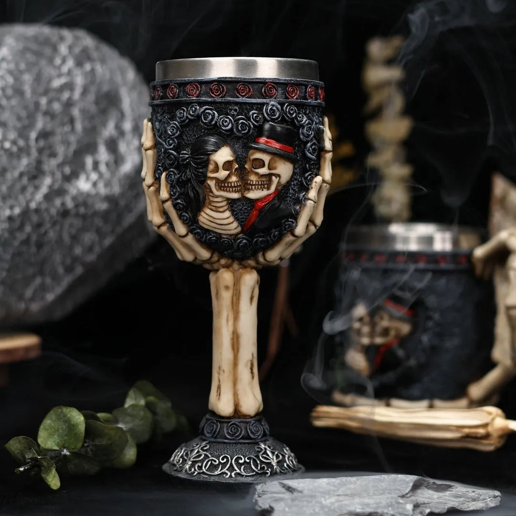 A pair of stainless steel wine glasses with a detailed red human skeleton pattern on a black background.