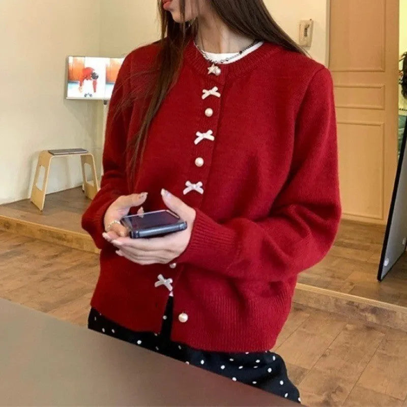 Women's solid colour cardigan sweater with bow-shaped pearl buttons on the front.