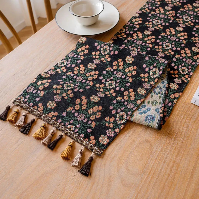 Nordic jacquard table runner with tassel trim in dark blue striped pattern laid on a wooden table.