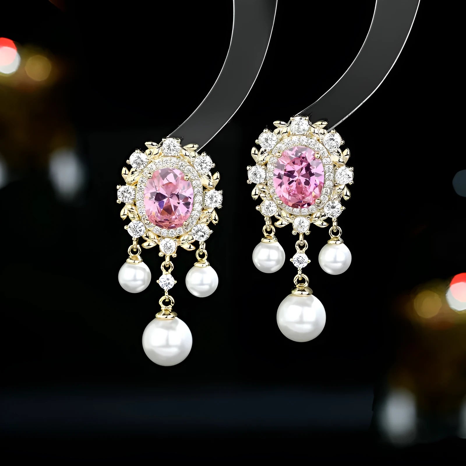 A pair of oval-shaped copper earrings with zircon inlay and a light-coloured pearl tassel.