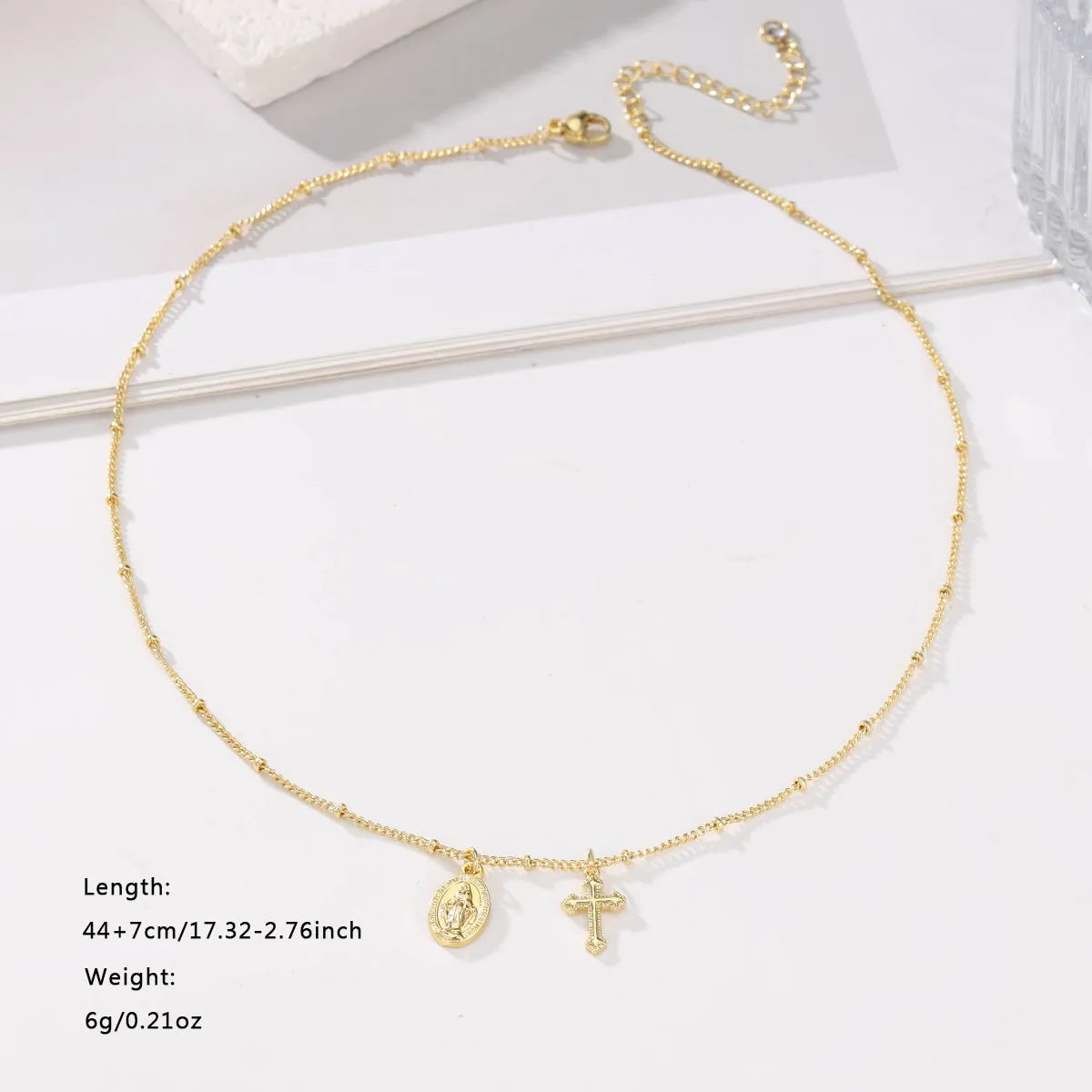 Gold-coloured geometric cross pendant necklace featuring the Virgin Mary, on a matching chain.