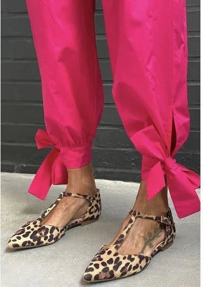 Leopard print women's pumps with a pointed toe, cross straps, and a low chunky heel on a rubber sole.