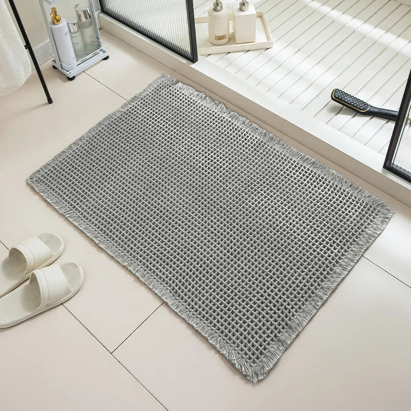 A square, checkered-pattern absorbent bathroom floor mat with a non-slip backing, shown in a neutral colour.