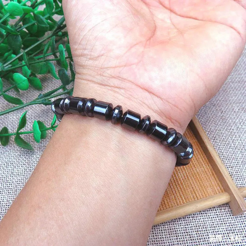Black pentagram design magnetic therapy bracelet made from magnetite and hematite stones on a wrist.