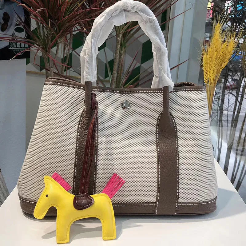 Women's canvas bucket tote bag with leather straps in black, shown with crossbody carry.
