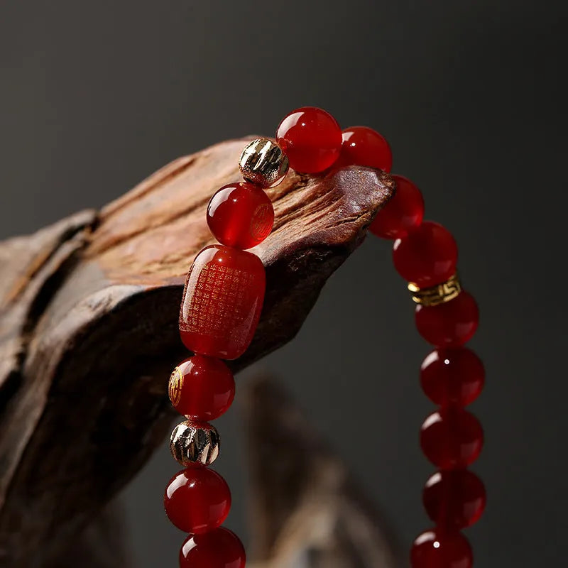 Agate Guanyin prayer bead bracelet in green or red on a wrist, showing auspicious patterns and charm.