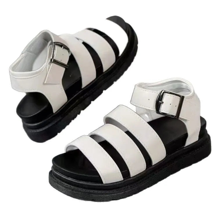 Thick-soled black buckle strap sandals on a beach, showing PU upper and rubber sole.