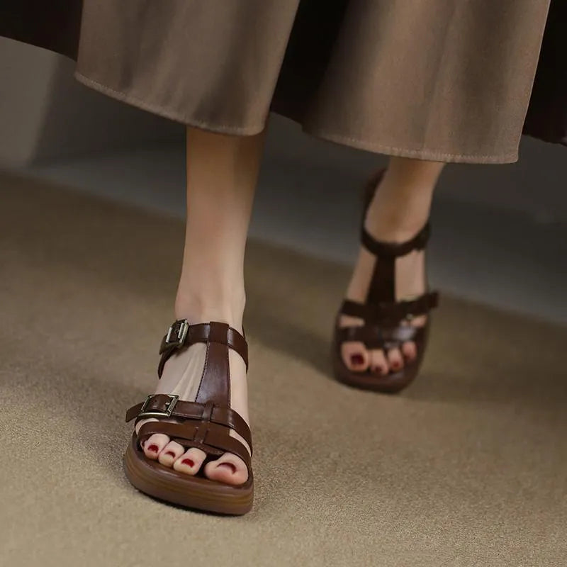 Women's black retro sandals with T-shaped buckle, chunky heel, and square open toe on a plain background.