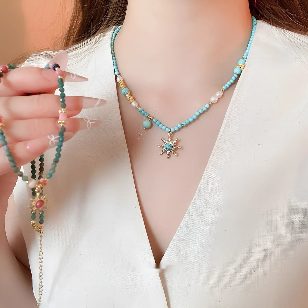 Freshwater pearl necklace with blue stone sun pendant on a gold-tone adjustable chain.
