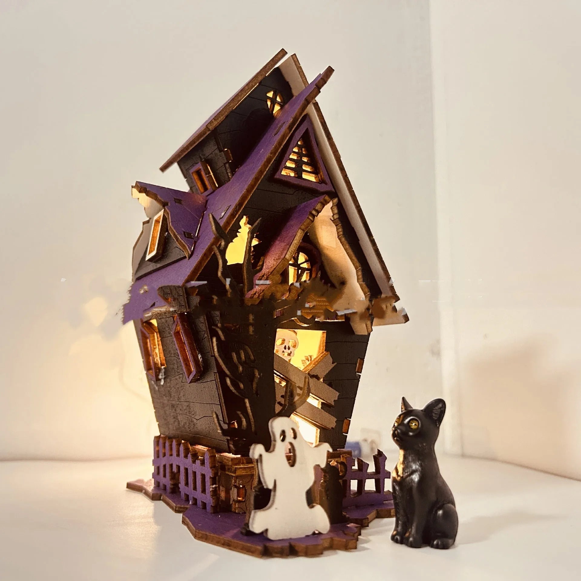 Unassembled DIY wooden haunted house Halloween decoration kit with glowing colour details.