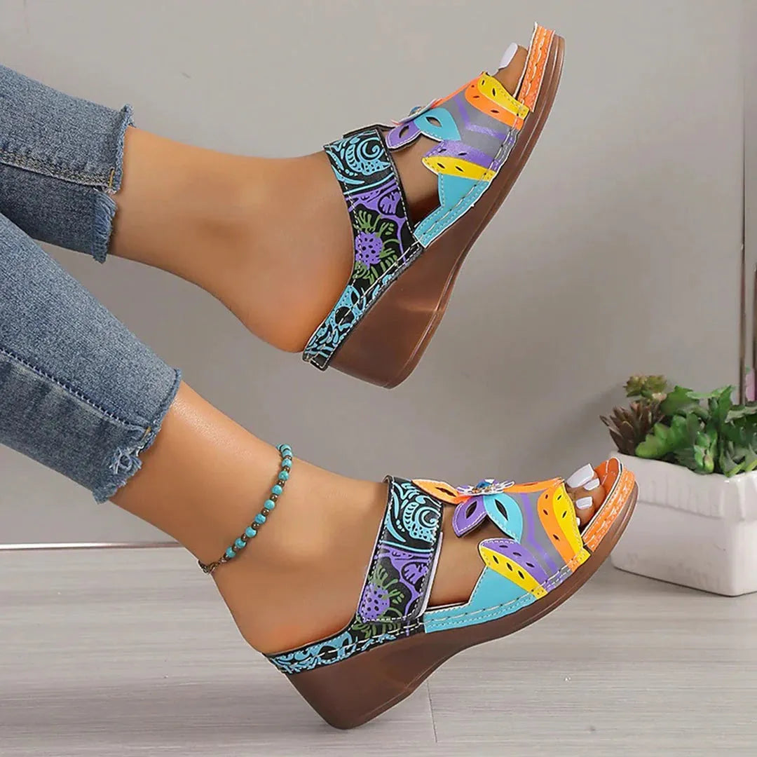 Coloured ethnic flat sandals with a slope heel and totem design on a cowhide upper.
