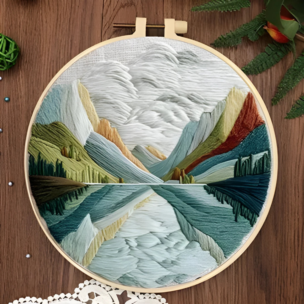 Embroidery DIY kit with bamboo frame, cotton fabric printed with a landscape scene, threads, and needles laid out