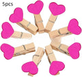 Set of five small wooden heart-shaped hair clips in various colours on a neutral background.