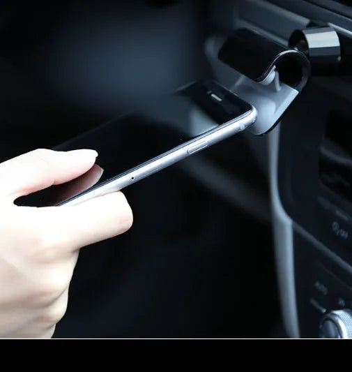 Black gravity car phone holder with 360-degree rotating head mounted on a car dashboard